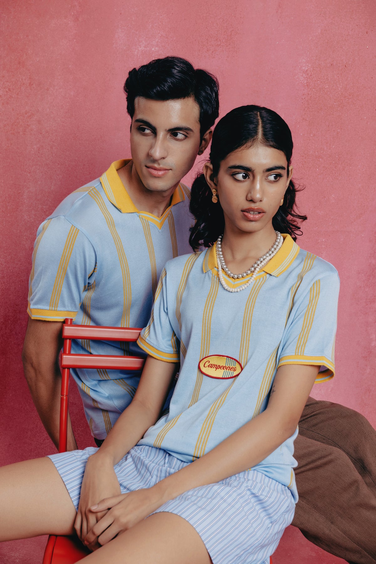 Two people wearing Campeones outfits with a red background