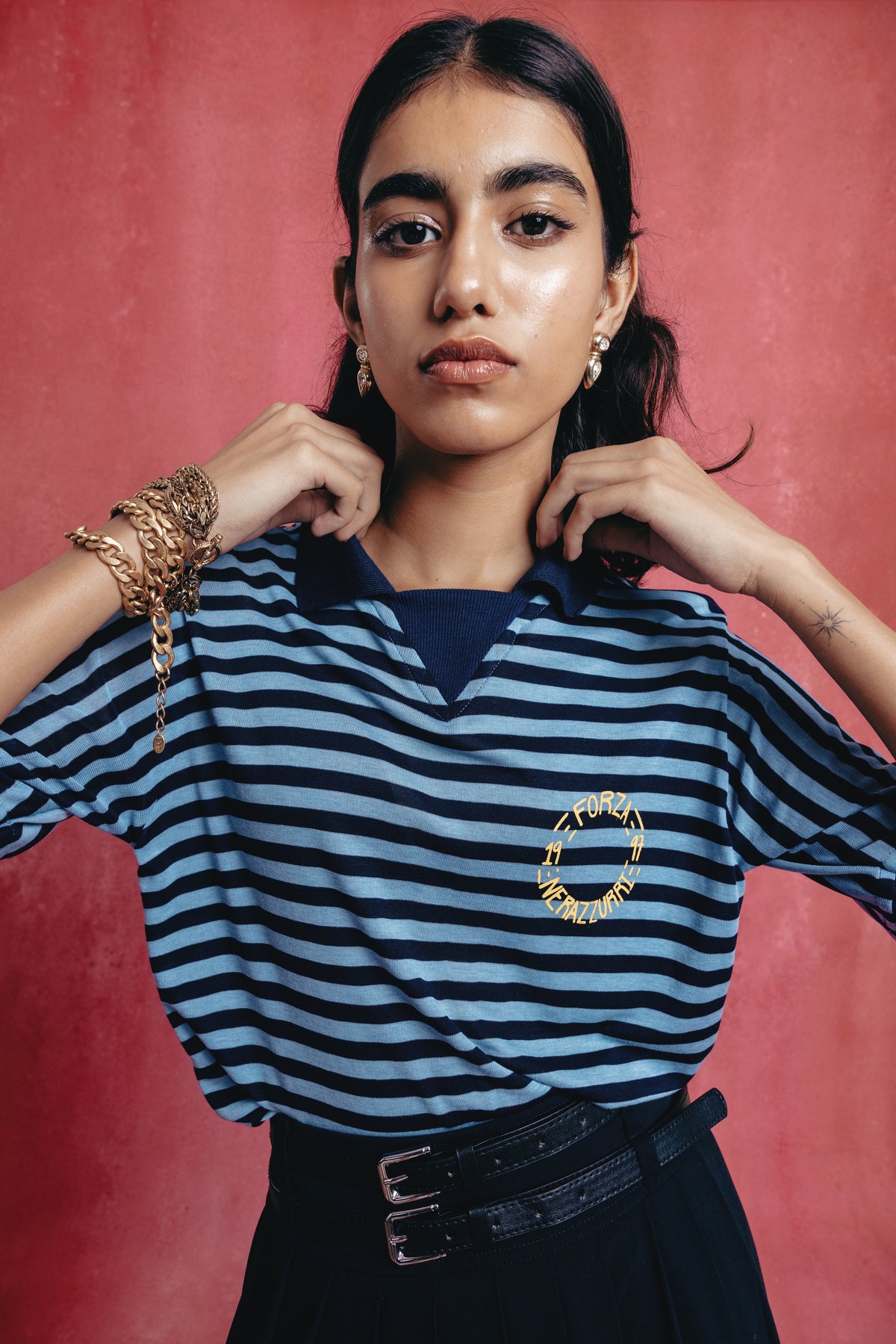 Girl wearing a the Nerazzurri blue and black striped shirt with a gold heart design against a pink background