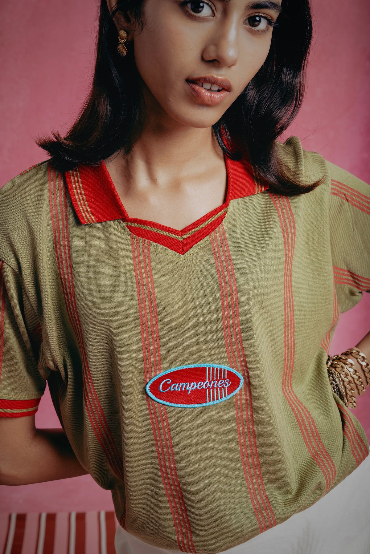 Girl wearing the Campeones a vintage-style shirt with a logo on a pink background